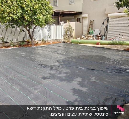 חצר עם יריעות פלסטיק שחורות ועצים מסביב